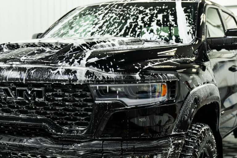 A black truck is being thoroughly washed inside a garage, showcasing the cleaning process